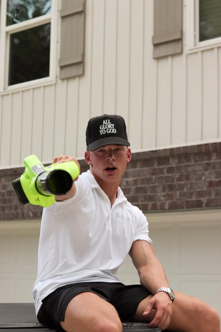 Man in white polo and black cap holding megaphone outdoors in front of white building