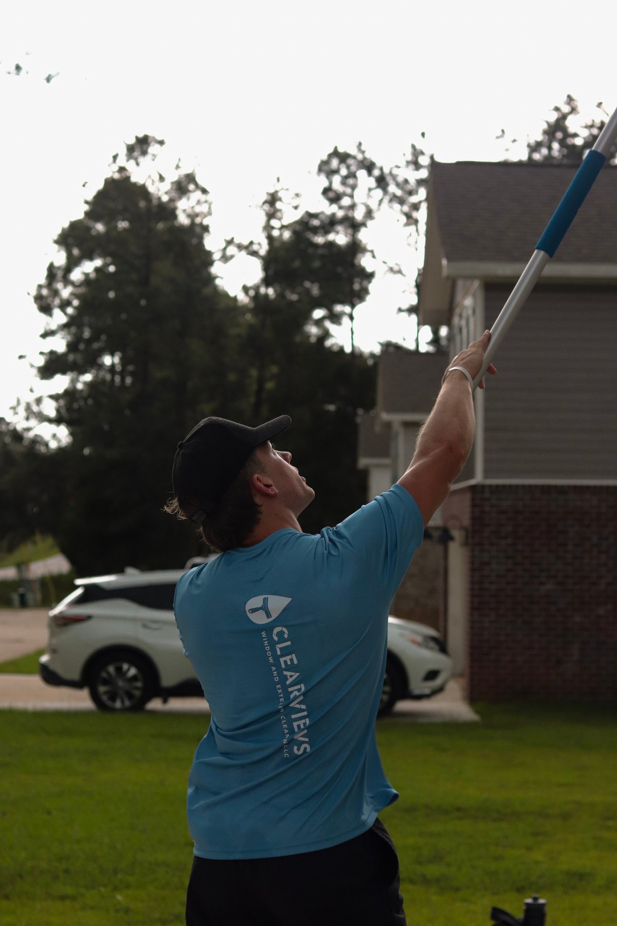 Clear Views technician using an extended pole to reach a second-story window