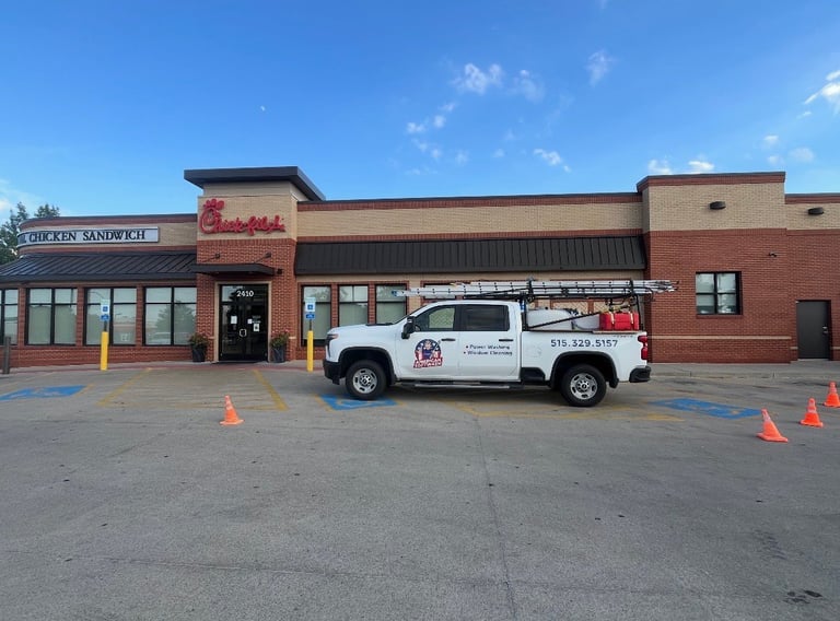 American Softwash service truck parked in front of a Chick-fil-A restaurant in Des Moines, Iowa — power washing and window cleaning branded on the side with the 515-329-5157 number
